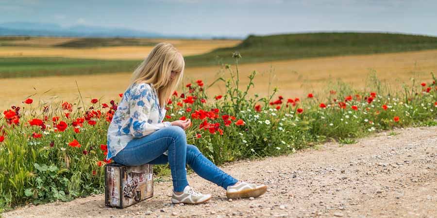 Woman waiting with a suitcase on the road.