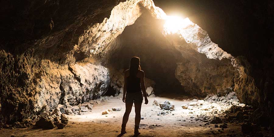 Woman standing in a cave with light coming in