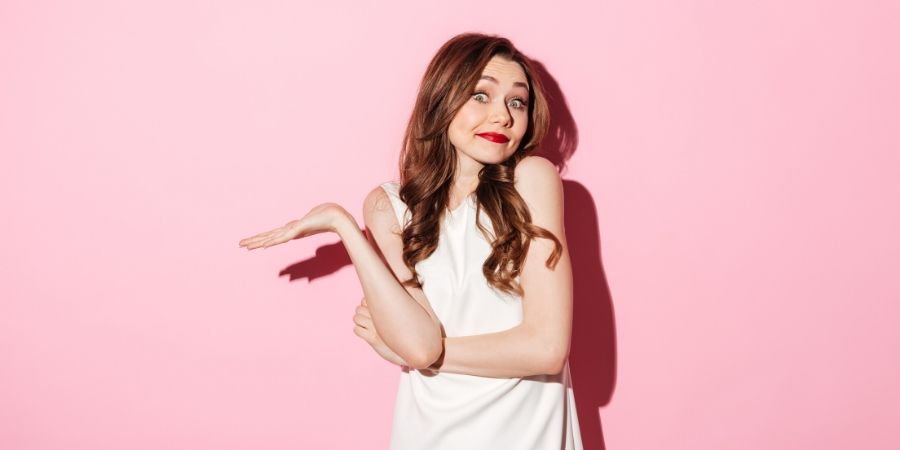 woman shrugging on pink background