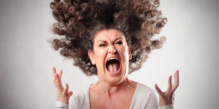 enraged woman with hair standing up and hands in air